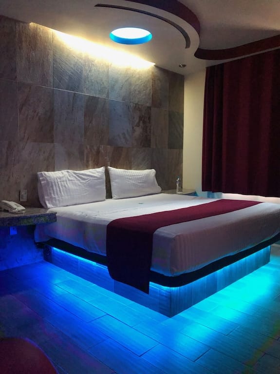 Neon-lit hotel room at Jard Inn, adult-themed hourly lodging, romantic getaway.