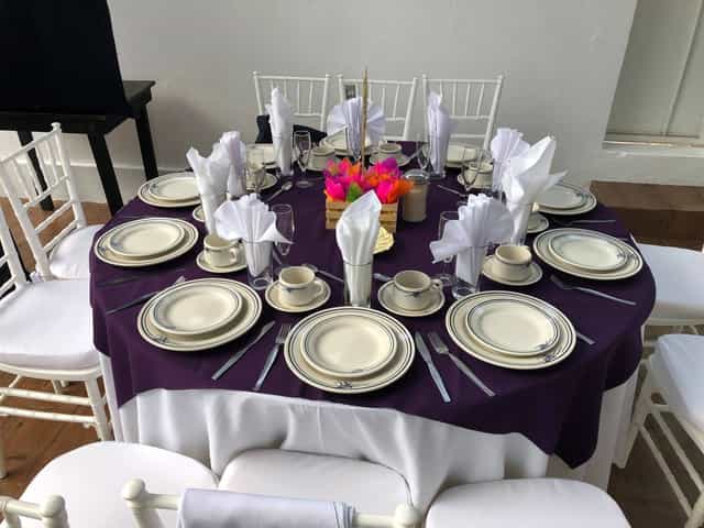 Function room with purple banquet setup, floral centerpieces, and Chiavari chairs for events.