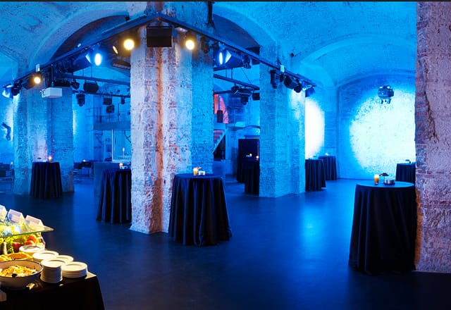 Versatile event space with blue lighting at Fàbrica Moritz for stylish corporate receptions.