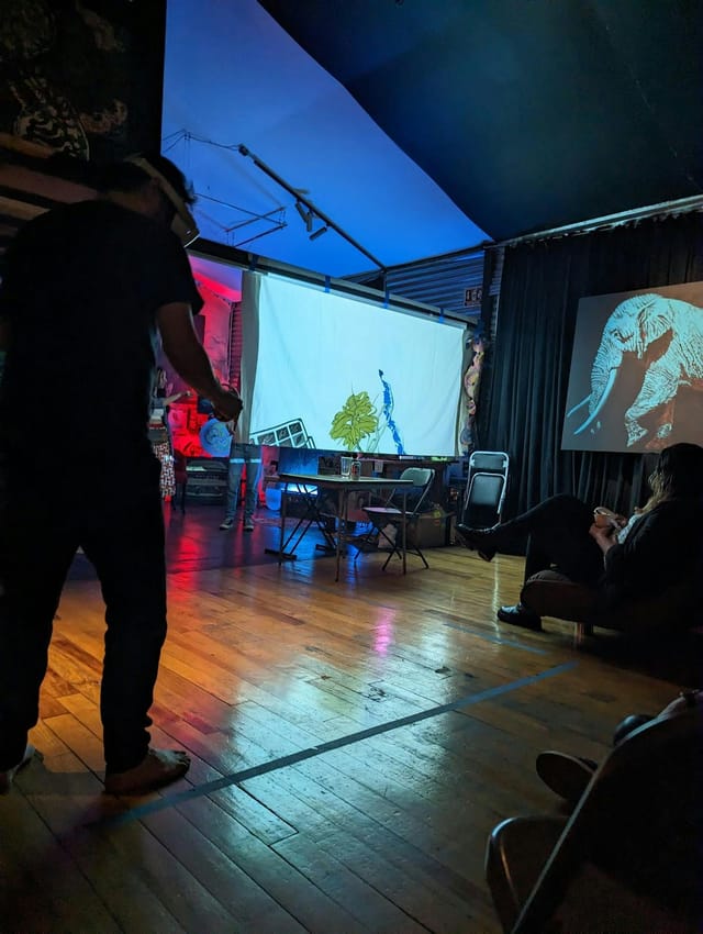 Guerilla art gallery event with atmospheric lighting, DIY staging, and projection screens.