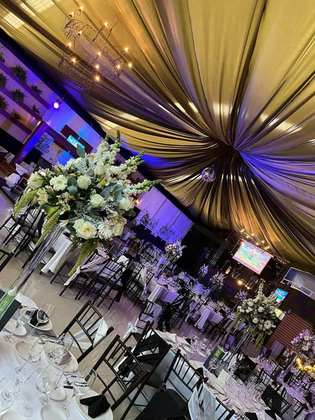 Gala event setup at Eventos Casablanca with ceiling draping and floral centerpieces.