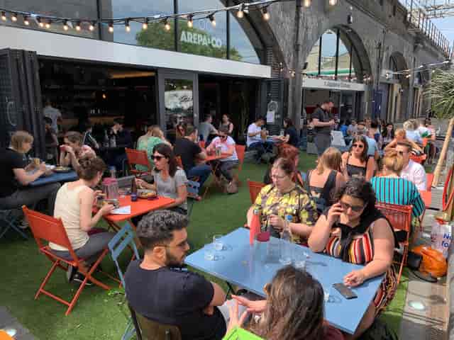 Outdoor terrace at Arepa & Co, vibrant networking event with colorful seating and greenery.