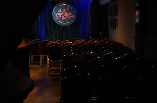 In Stitches Comedy club theater stage with focused lighting for intimate stand-up comedy shows.
