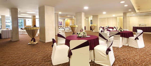Maurya Banquets event space with cocktail tables and structural pillars for corporate event rental.