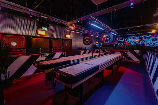 Industrial-themed Roxy Ball Room Den with dual shuffleboard for corporate teambuilding events.