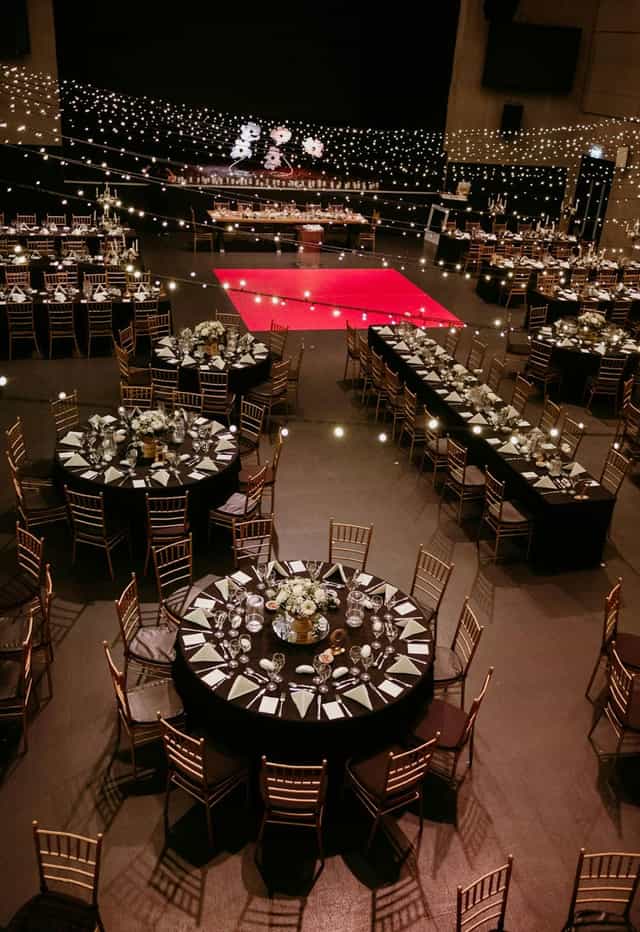 Black and gold gala setup with red dance floor for corporate events and formal banquets.