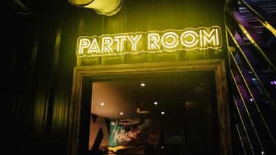 Karaoke room at King Pins Manchester with vibrant neon sign for fun celebrations.