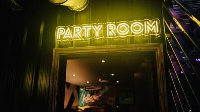 Karaoke room at King Pins Manchester with vibrant neon sign for fun celebrations.