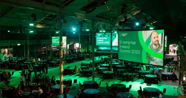 "Main Hall at Enterprise Ireland Summit 2023 with sleek staging and vibrant green lighting"