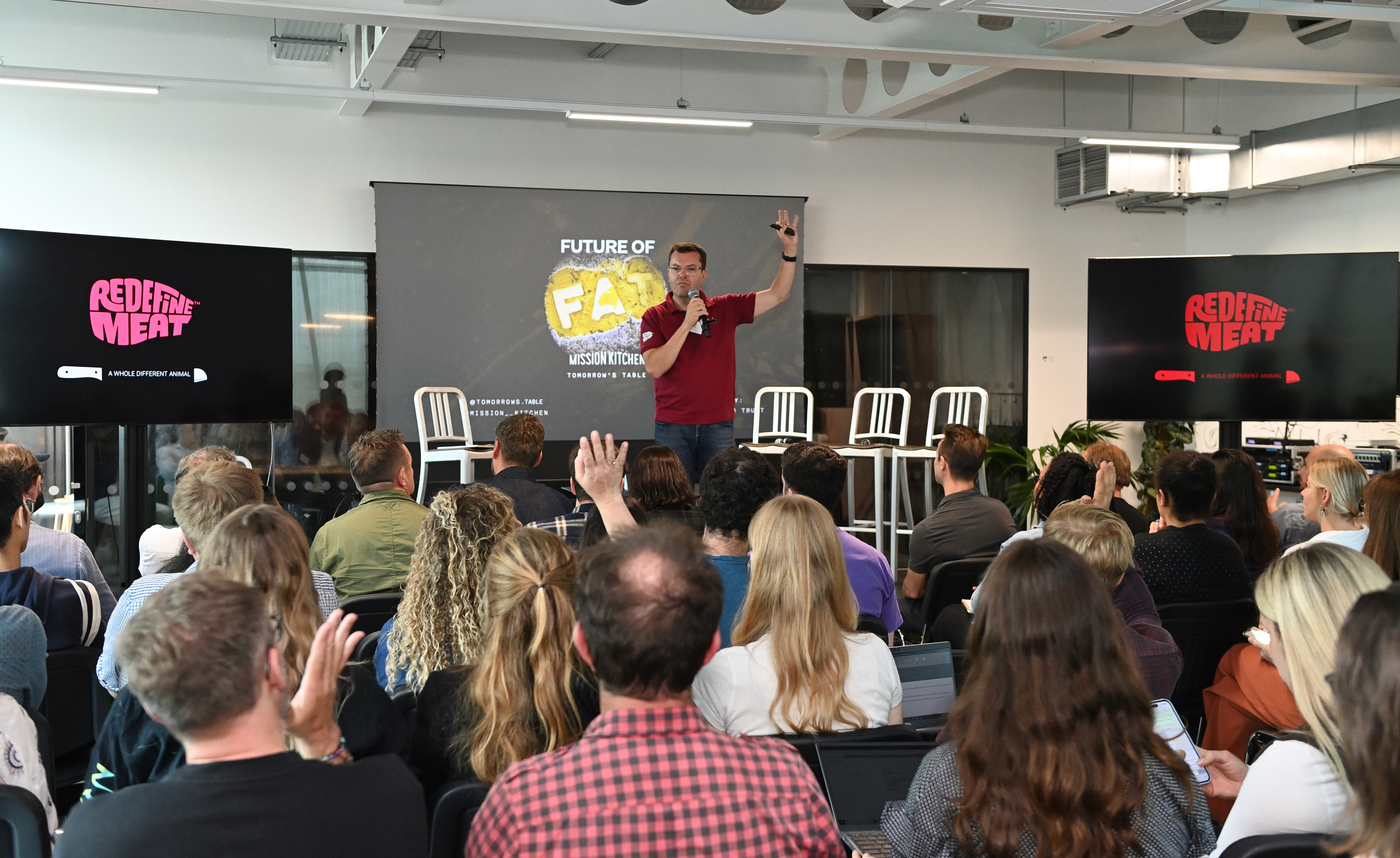 Dynamic speaker engaging audience in modern Glass Room at Mission Kitchen event. - Banner