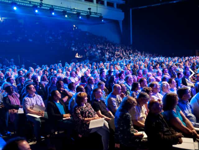 Packed auditorium at Brighton Centre with vibrant stage lighting for engaging events.