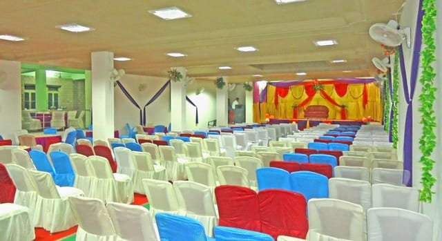 Theater-style banquet hall with vibrant chair covers for weddings and corporate events.