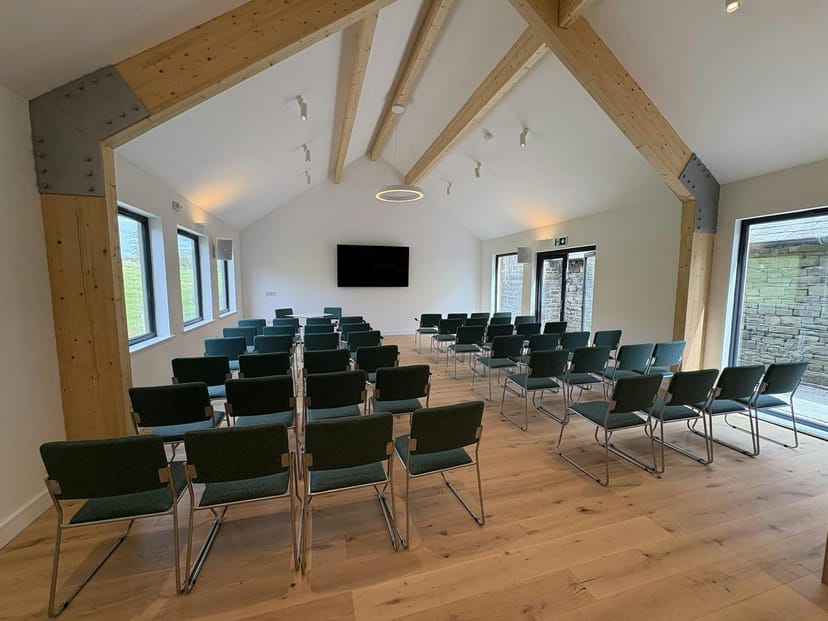 Modern meeting room with vaulted ceilings and kitchen, ideal for workshops and presentations.