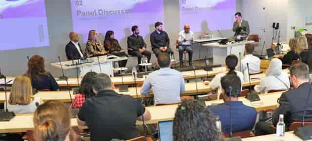 Panel discussion in Motor Hub Warwick Board Room 2 with tiered seating for academic conferences.