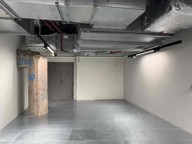 Urban Village Hall minimalist event space with exposed utilities for versatile setups.