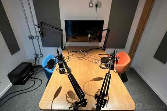 Modern podcast studio with microphones and colorful chairs for creative meetings.