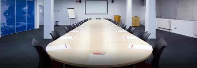 Conference room setup with oval table, notepads for meetings and presentations.