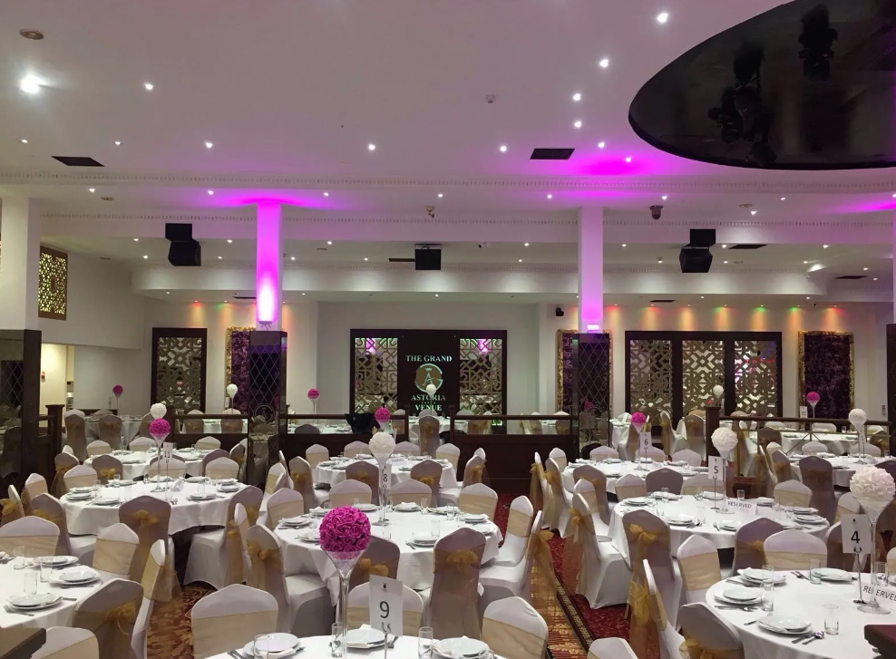 Elegant wedding event space with floral centerpieces at The Grand Astoria venue. - Banner