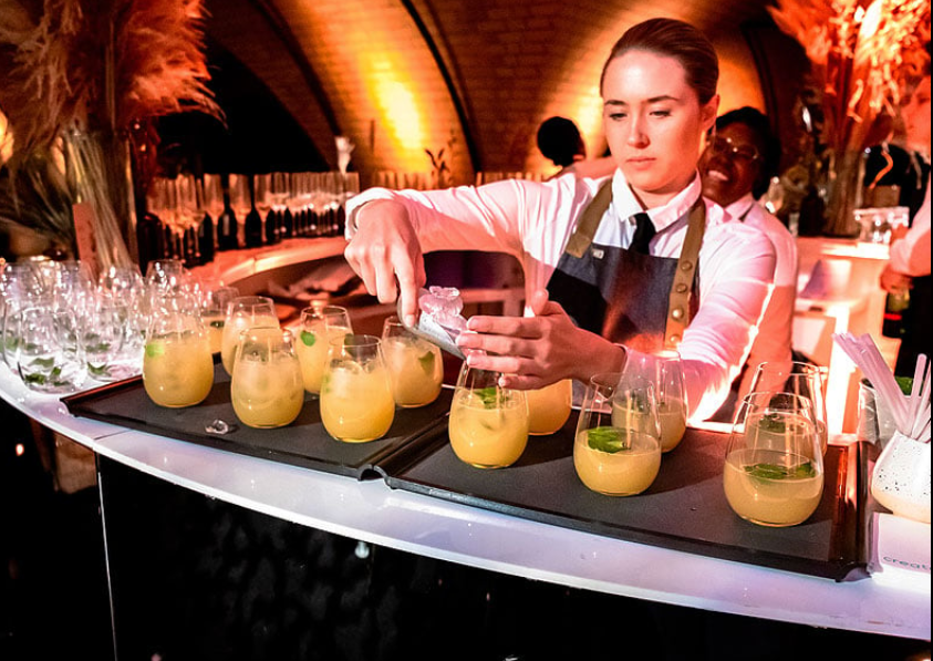 Skilled bartender crafting cocktails at an upscale mobile bar service event.