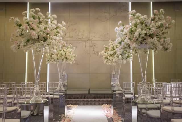 Luxury wedding ceremony with tiered floral pedestals and ghost chairs at Four Seasons Toronto.