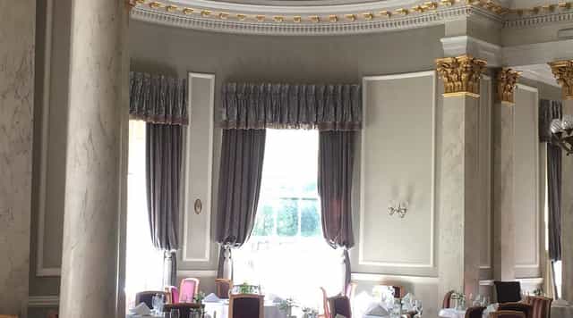 Elegant ballroom with gold molding and marble pillars for luxury galas and executive dining.