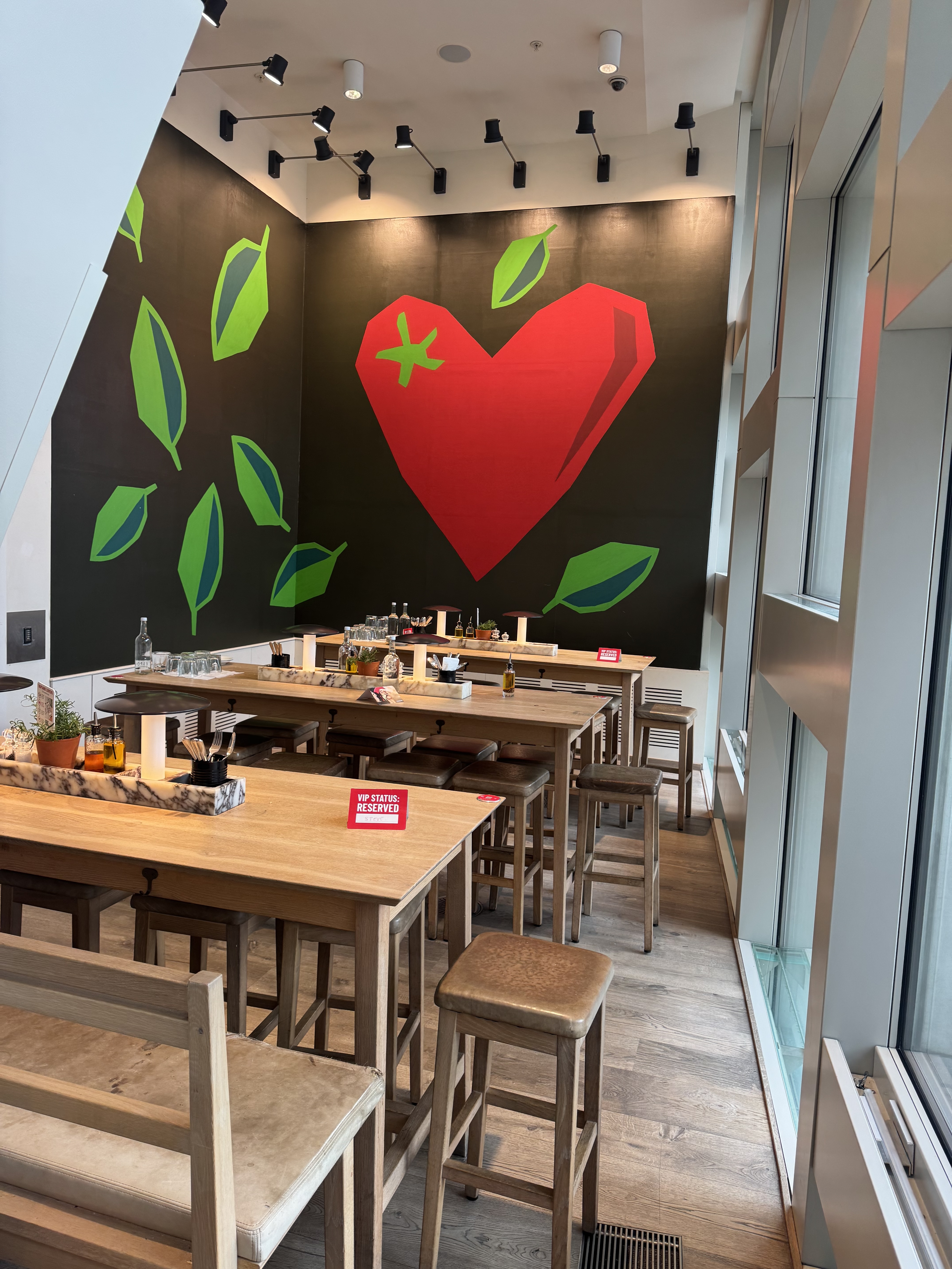 Vibrant meeting space at Vapiano Tottenham Court with heart mural, ideal for gatherings.