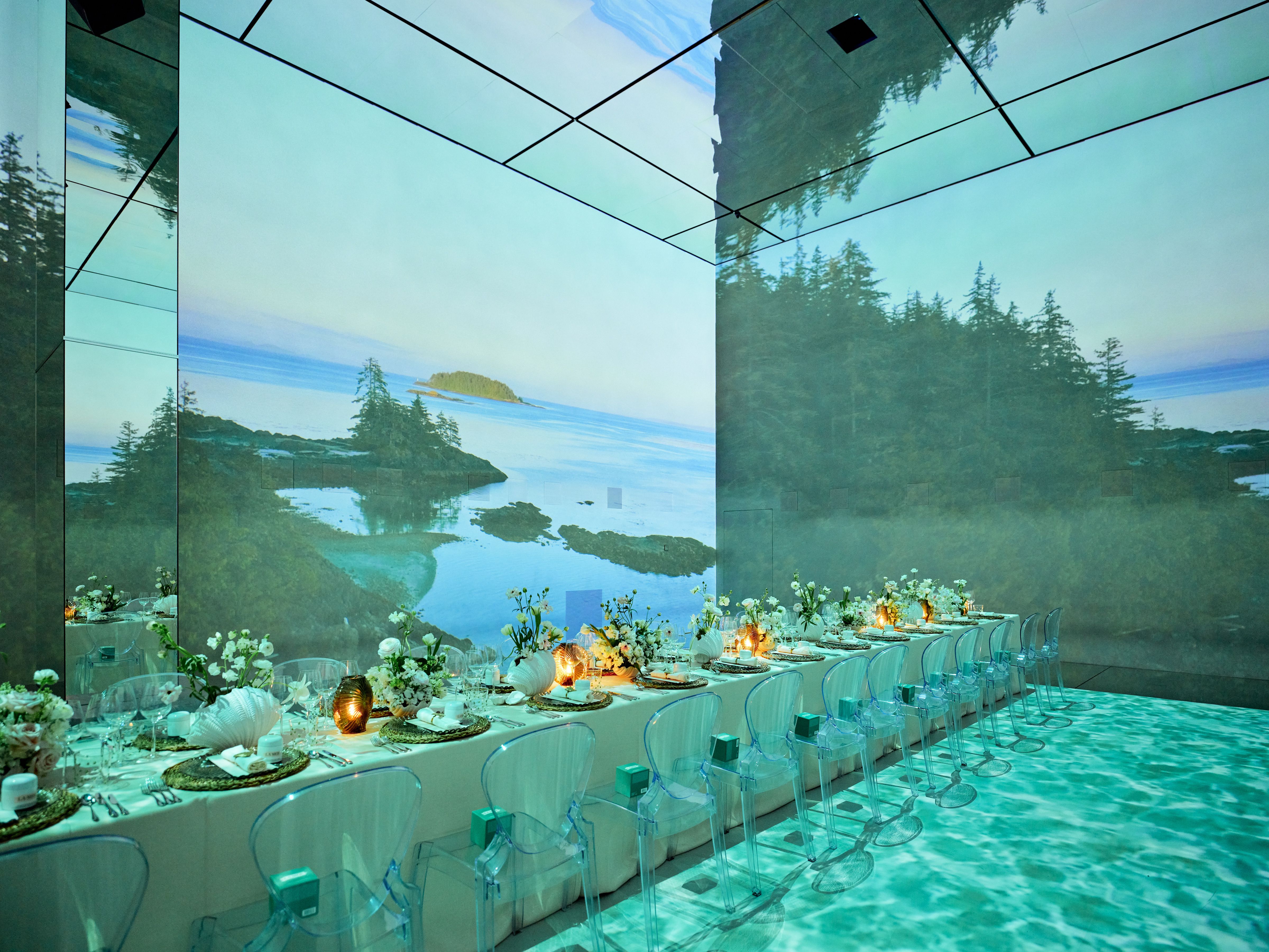 Event space with long dining table and nature projections for upscale gatherings. - Banner