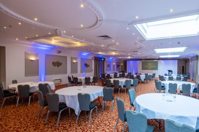 Grand Prix Suite at Whittlebury Park: elegant event space with round tables and blue lighting.