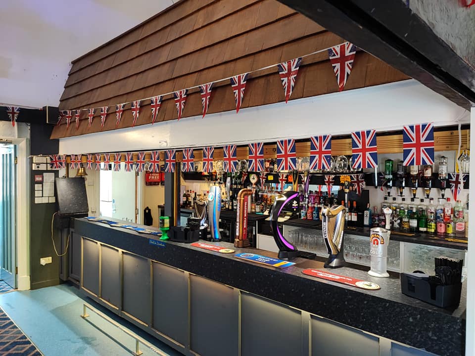 "Tythe Barn bar area with British flags, perfect for social events and gatherings."