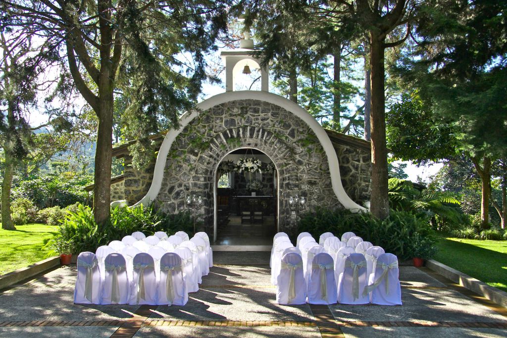Charming outdoor wedding venue with rustic stone structure and lush greenery.