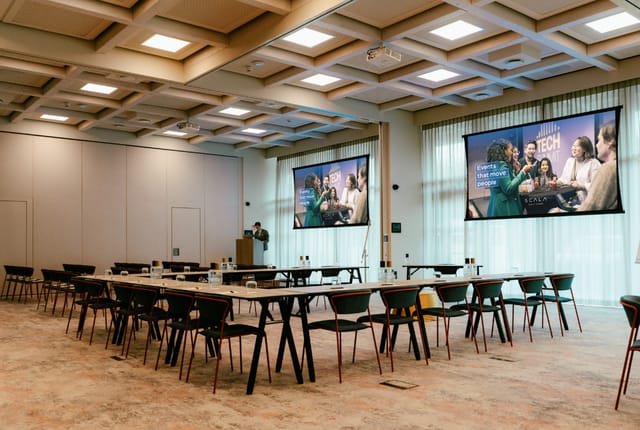 Modern conference room with long tables for tech events and corporate meetings.