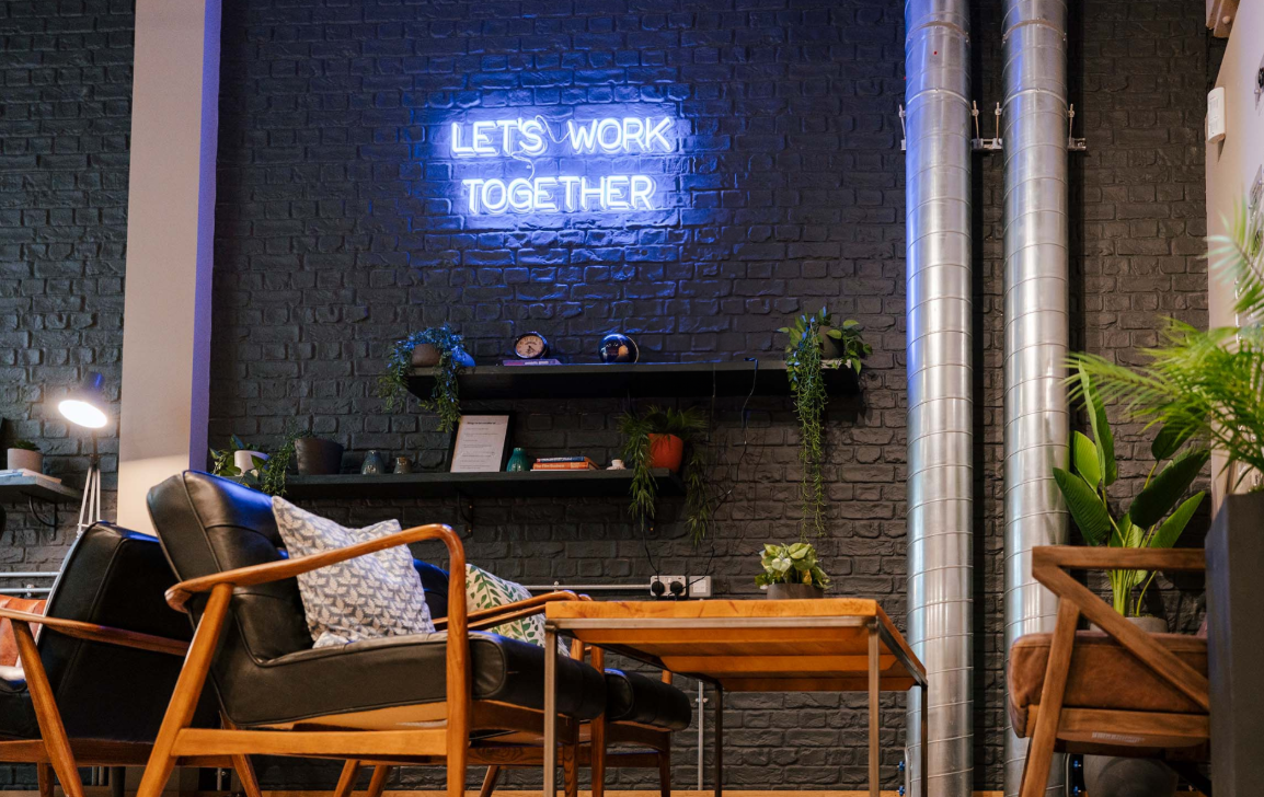 Modern collaborative workspace with neon sign, ideal for team-building and workshops. - Banner