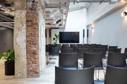 Modern industrial meeting space with exposed brick, perfect for tech workshops and presentations.
