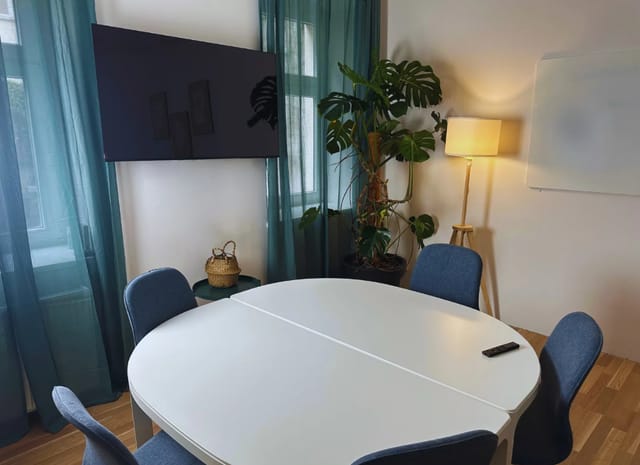Modern seminar room with round table, natural light, ideal for collaborative meetings.