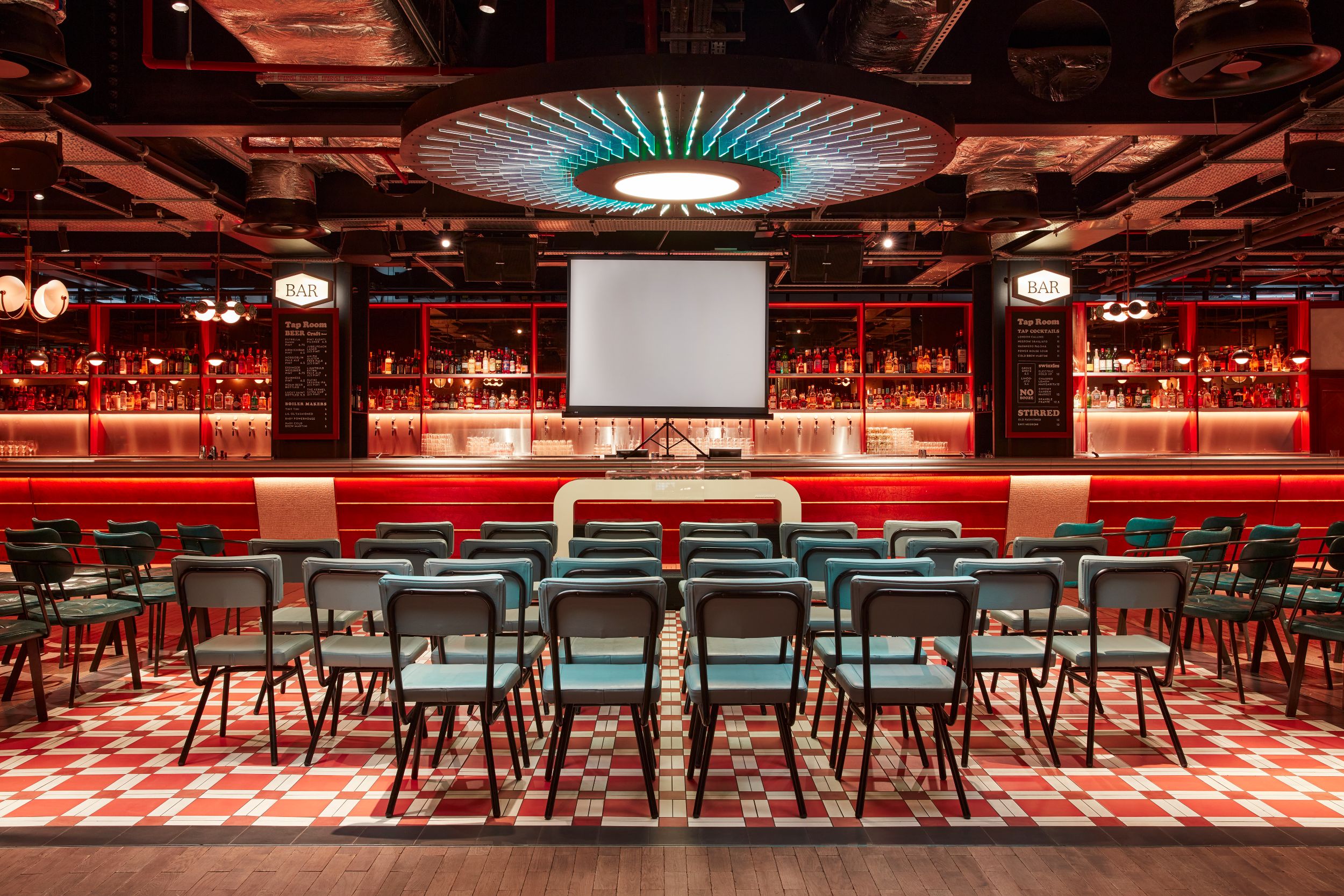 "Event space in Arcade Battersea with bar backdrop, ideal for presentations and meetings."
