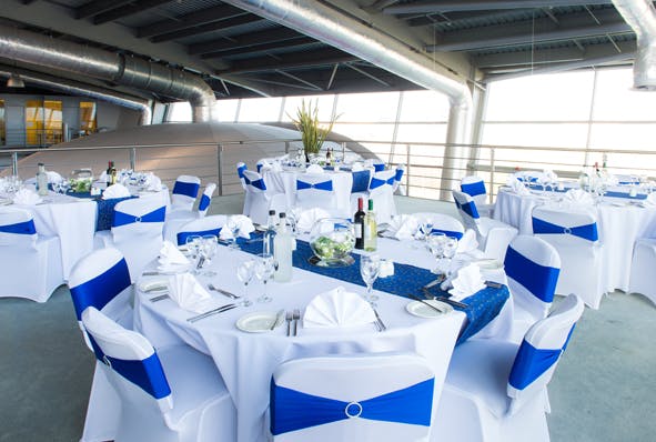 Elegant event space with round tables, white linens, and blue accents for corporate gatherings.