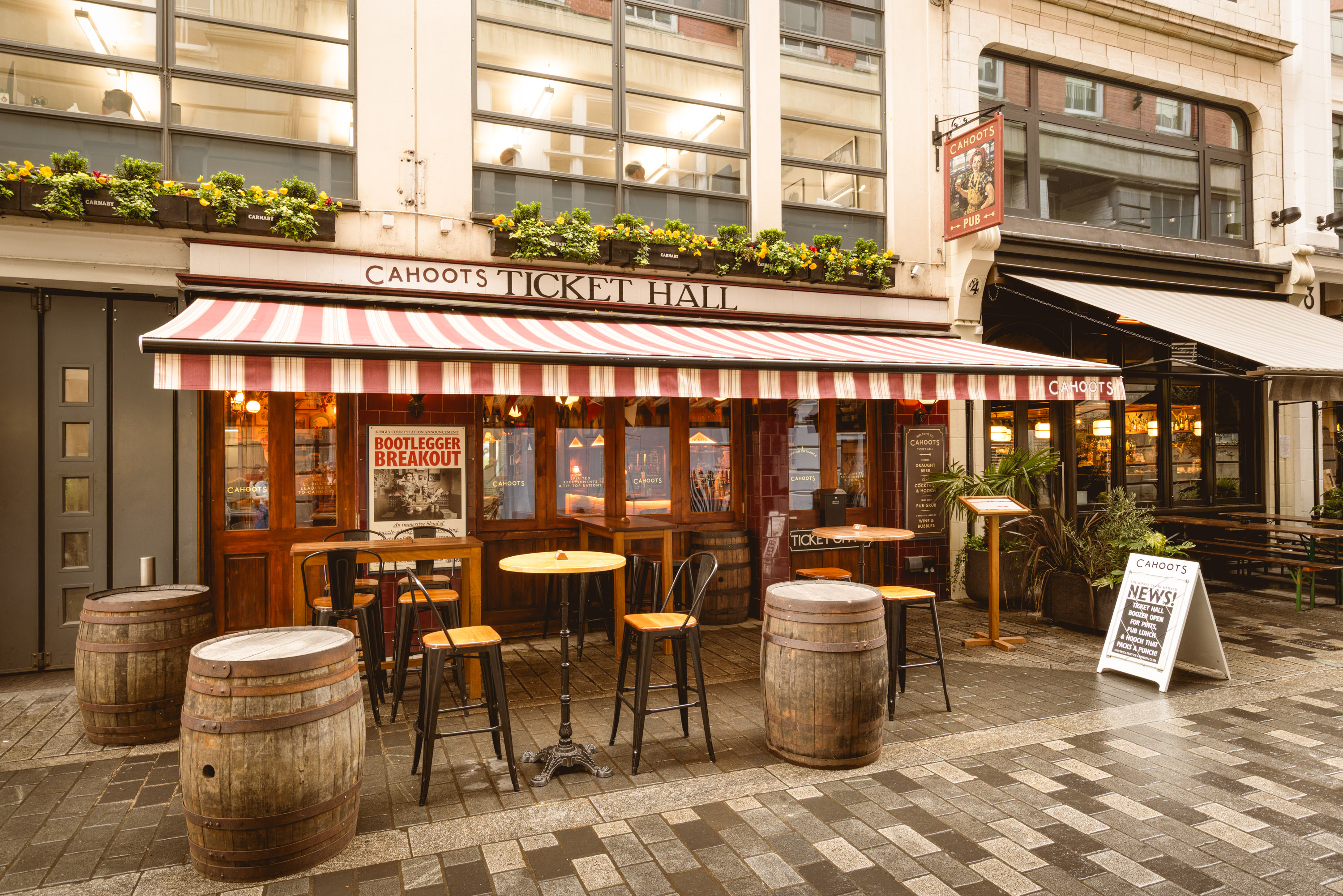 Outdoor dining at Cahoots pub with striped awning, perfect for networking events.