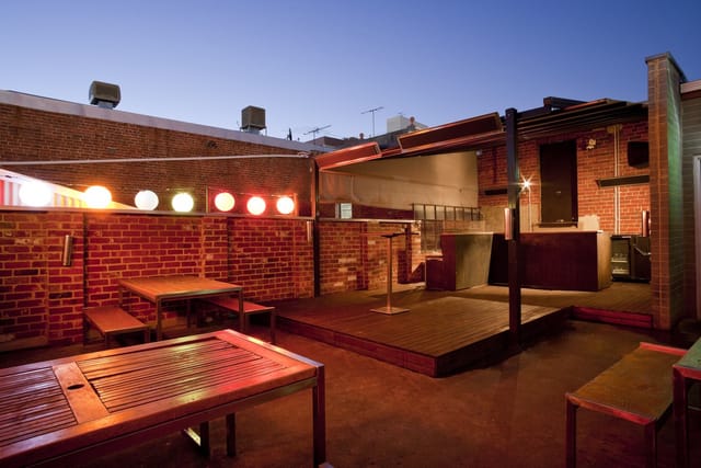 Industrial rooftop terrace venue with a stage and bar for networking mixers and evening receptions.