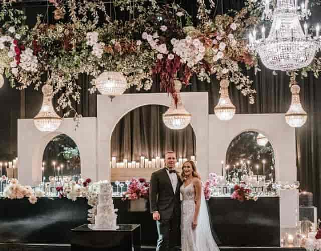 Wedding reception backdrop with crystal chandeliers and floral arch at Ivy Gardens for events.