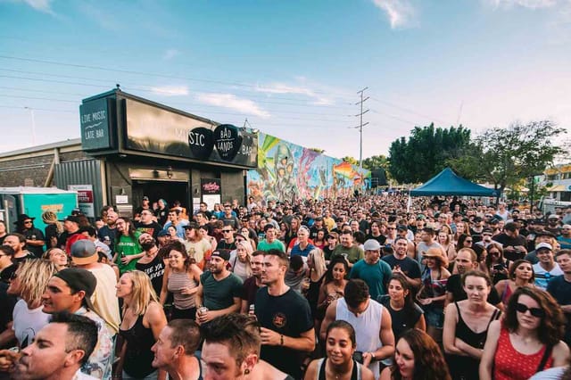 Crowd at Badlands Bar festival with mural backdrop, ideal for outdoor event activation.