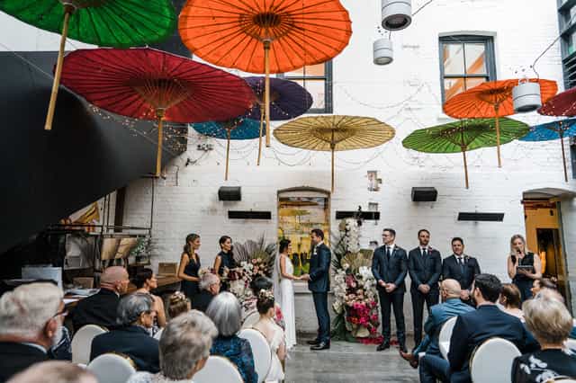 Long Chim industrial courtyard wedding with vibrant umbrella ceiling decor.