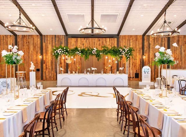 Rustic-chic Sandalera Room wedding venue with custom dance floor and floral head table.
