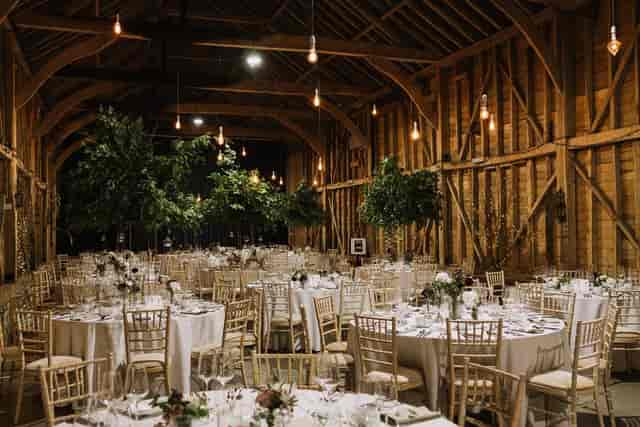 Rustic timber-framed barn venue at Childerley Hall with indoor trees for luxury event dining.