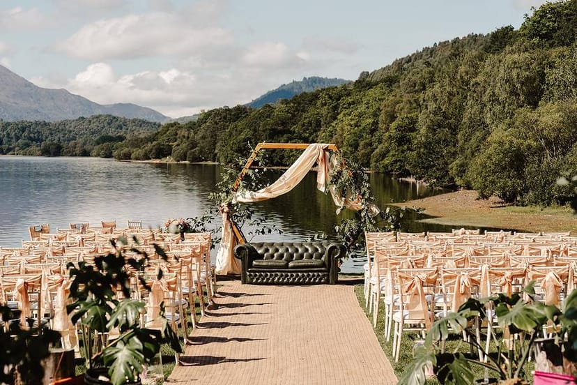 Outdoor wedding ceremony at Venachar Lochside with statement tufted leather loveseat.