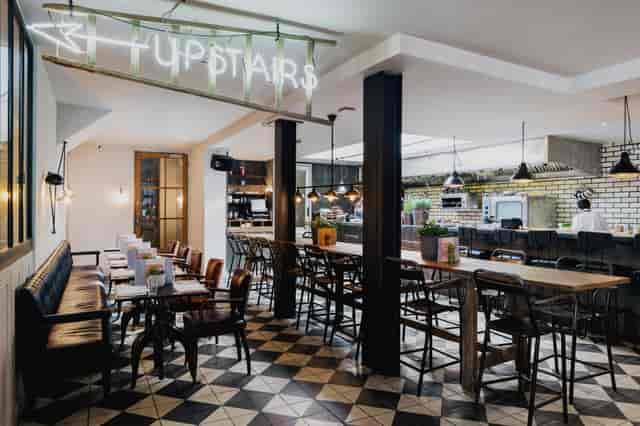 Industrial-chic venue with communal bar seating, ideal for networking receptions and breakouts.