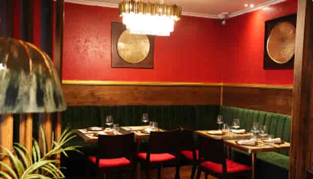 Intimate dining venue with red walls and green seating for upscale meetings or events.