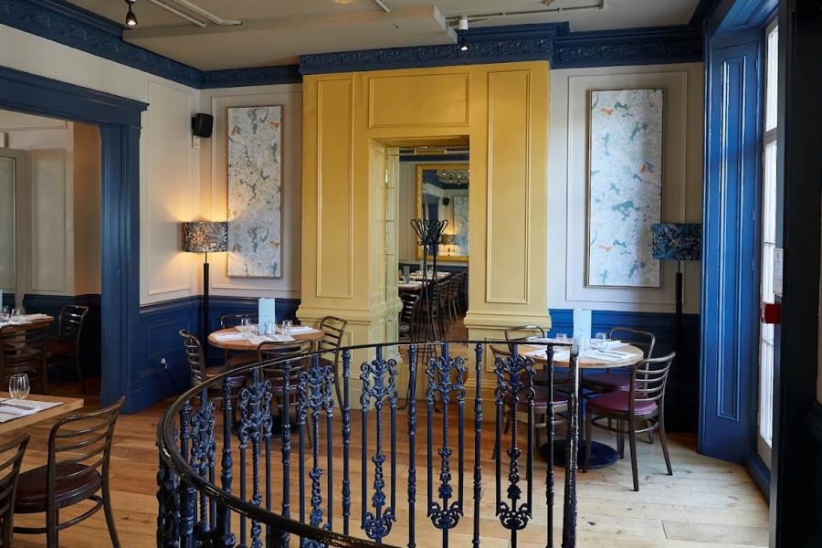 Stylish dining space with yellow and blue accents for upscale gatherings in Côte Brasserie.