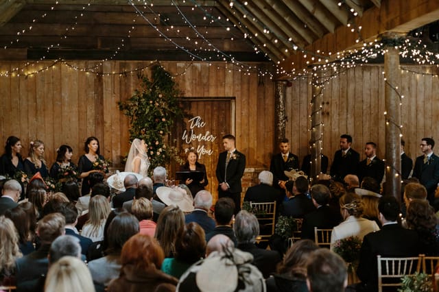 Beautiful wedding venue at The Byre, featuring rustic wood backdrop and fairy lights.