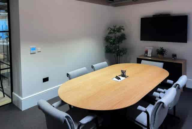 Modern conference room with oval wooden table for collaborative meetings and presentations.