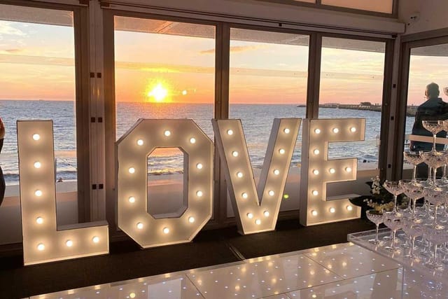 LOVE marquee sign at sunset waterfront beach wedding event for romantic photo op.